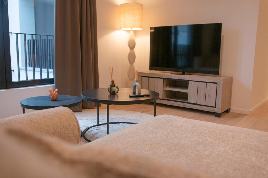 a living room with a television and a couch and a table at Central Chic Antwerp 201 in Antwerp