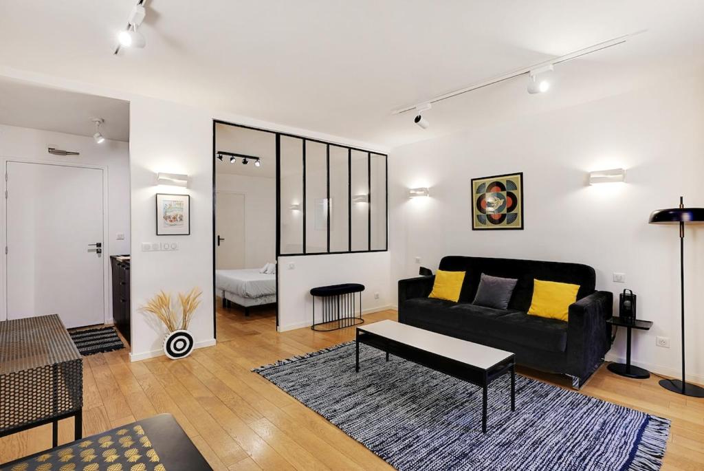 un salon avec un canapé noir et une table dans l'établissement LE MARAIS - NEW APARTMENT Haut de Gamme, à Paris
