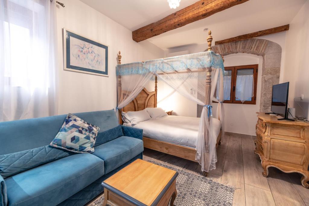 a living room with a blue couch and a bed at Chambre du Puits du Couvent in Narbonne