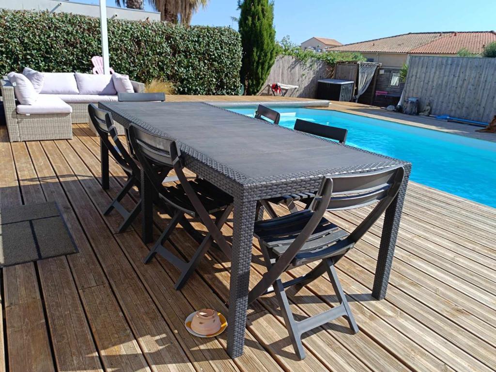- une table et des chaises noires à côté de la piscine dans l'établissement St Cyprien Superbe villa 4 chambres et piscine, à Saint-Cyprien