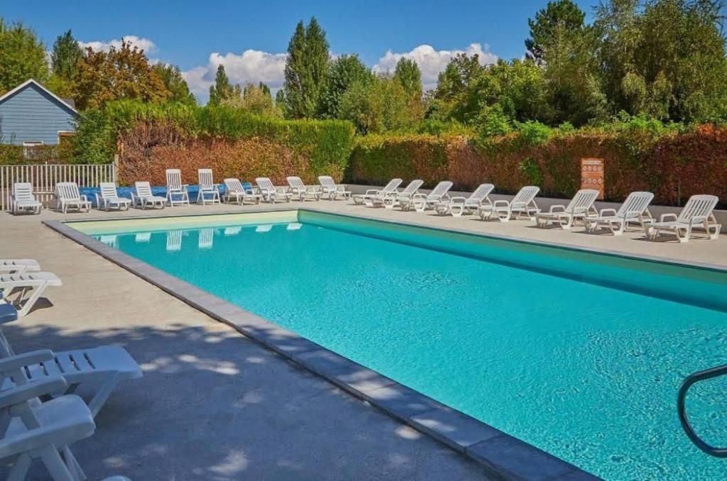 a swimming pool with chaises and lounge chairs next to it at Paris Eure Gestion - Mobilhome 6P proche étang et rivière in Ivry-la-Bataille