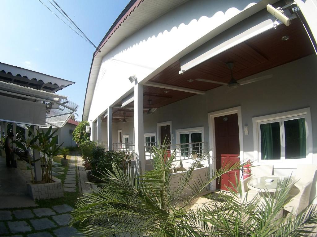 a white house with a red door and a porch at Langkawi Chantique in Pantai Cenang