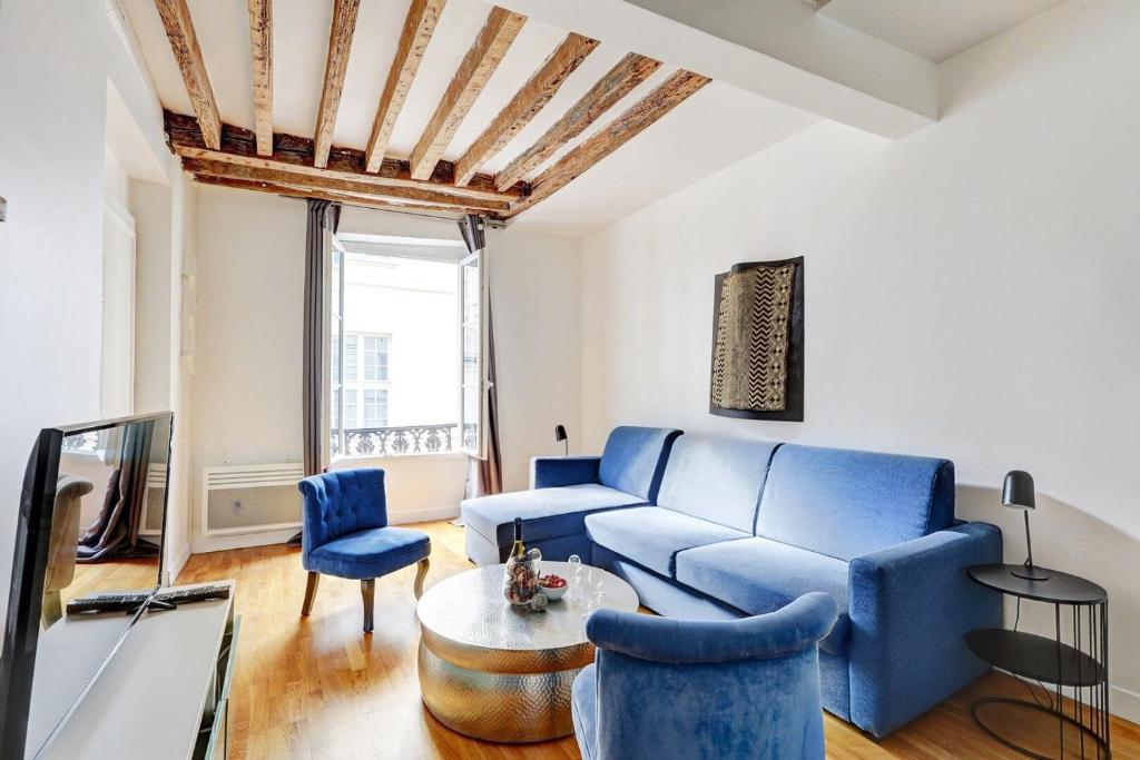 un salon avec un canapé bleu et des chaises dans l'établissement Bluestay 284 - Superbe Appartement dans le Marais, à Paris