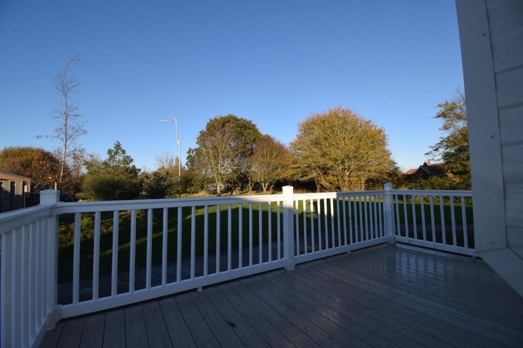 eine Holzterrasse mit einem weißen Geländer an einem Haus in der Unterkunft 25 Poplars Way Walton on Naze in Walton-on-the-Naze