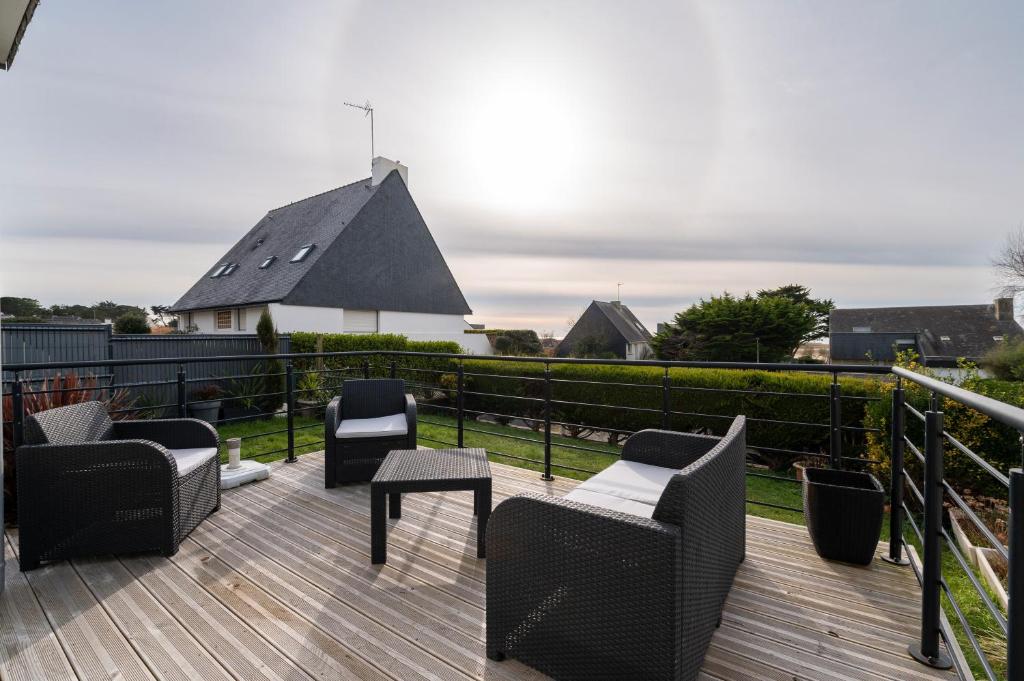 eine Terrasse mit Stühlen und Tischen auf einer Holzterrasse in der Unterkunft Maison Guidel plage - Vue mer in Guidel