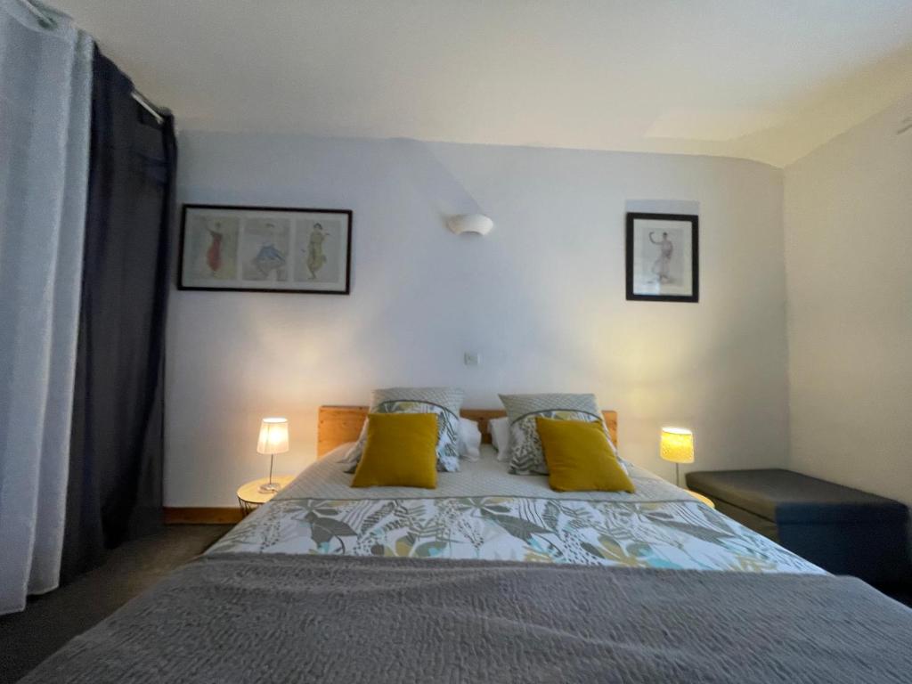 une chambre avec un grand lit avec des oreillers jaunes dans l'établissement Joli appartement rénové avec jardin clos, à La Tremblade