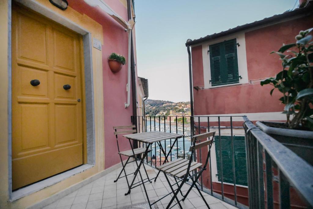 un tavolo e sedie su un balcone con porta gialla di Anciüetta a Lerici