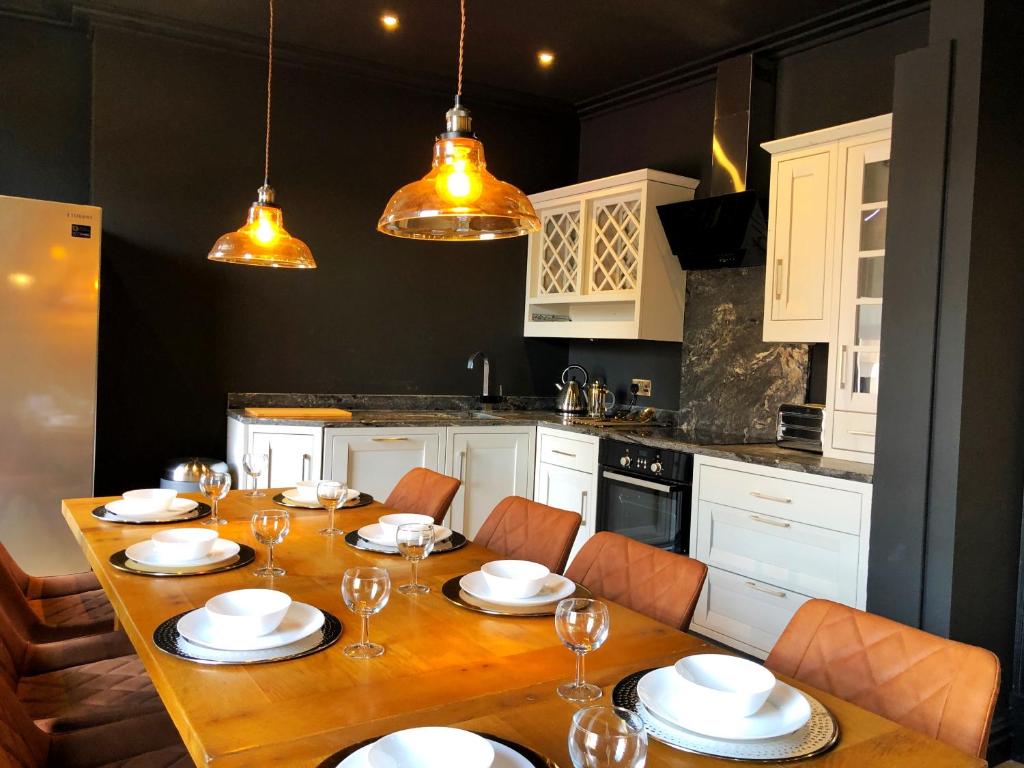 a kitchen with a wooden table with chairs and white cabinets at The Residence Sasco Apartments in Blackpool