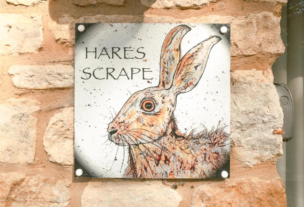 a picture of a rabbit on a brick wall at Hares Scrape at Tove Valley Cottages in Towcester