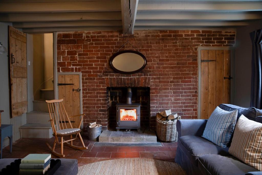 un salon avec une cheminée en briques et un canapé dans l'établissement Worstead Cottage by Big Skies Cottages, à Worstead