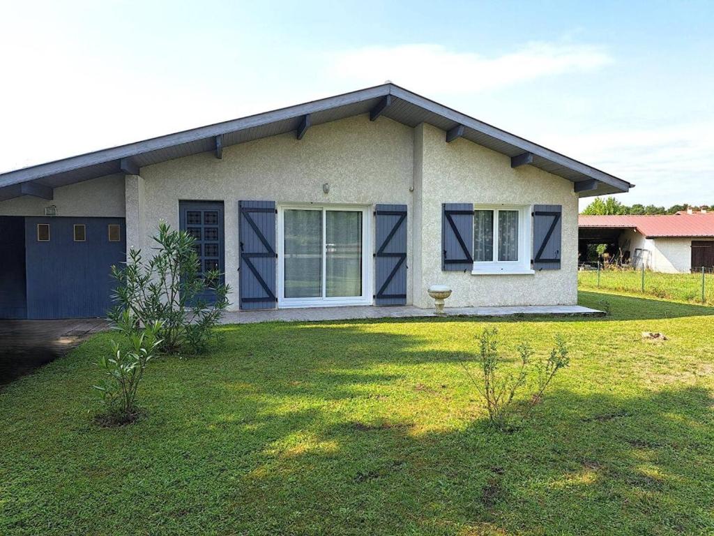 une petite maison avec une cour en gazon devant elle dans l'établissement Sérénité, à Lit-et-Mixe