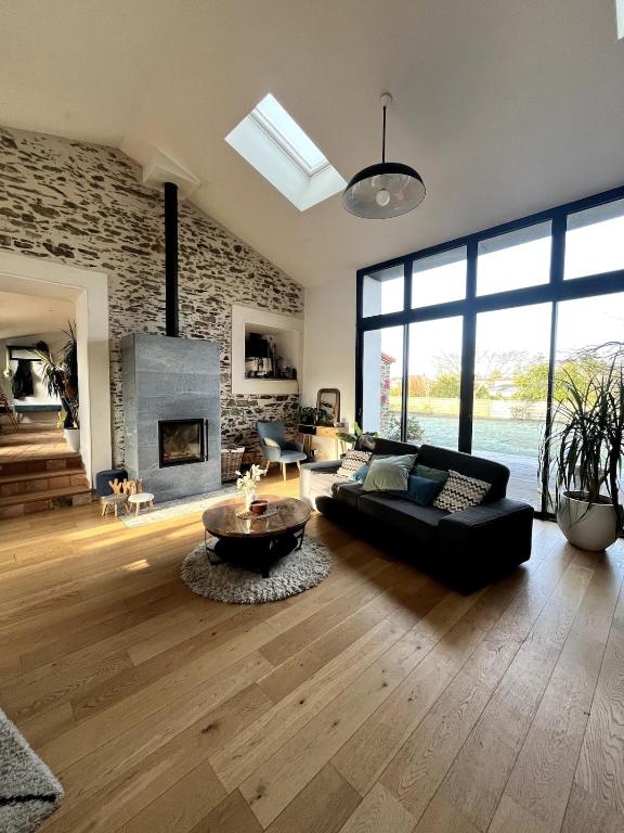 - un salon avec un canapé noir et une cheminée dans l'établissement Divatte, Belle maison 8 pers en bord de Loire, à Divatte sur Loire