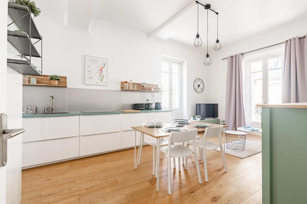 une cuisine avec des armoires blanches et une table et des chaises dans l'établissement Le 37 - Hypercenter & Modern, à Dijon