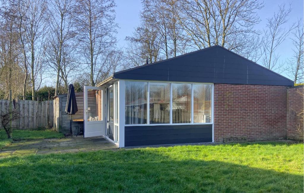 a small house with a large window on a yard at Pet Friendly Home In Dirkshorn in Dirkshorn