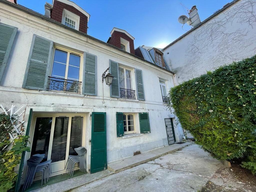 Un ancien bâtiment blanc avec des volets et des chaises verts dans l'établissement Appartio - Grande maison proche PARIS, à Villiers-le-Bel