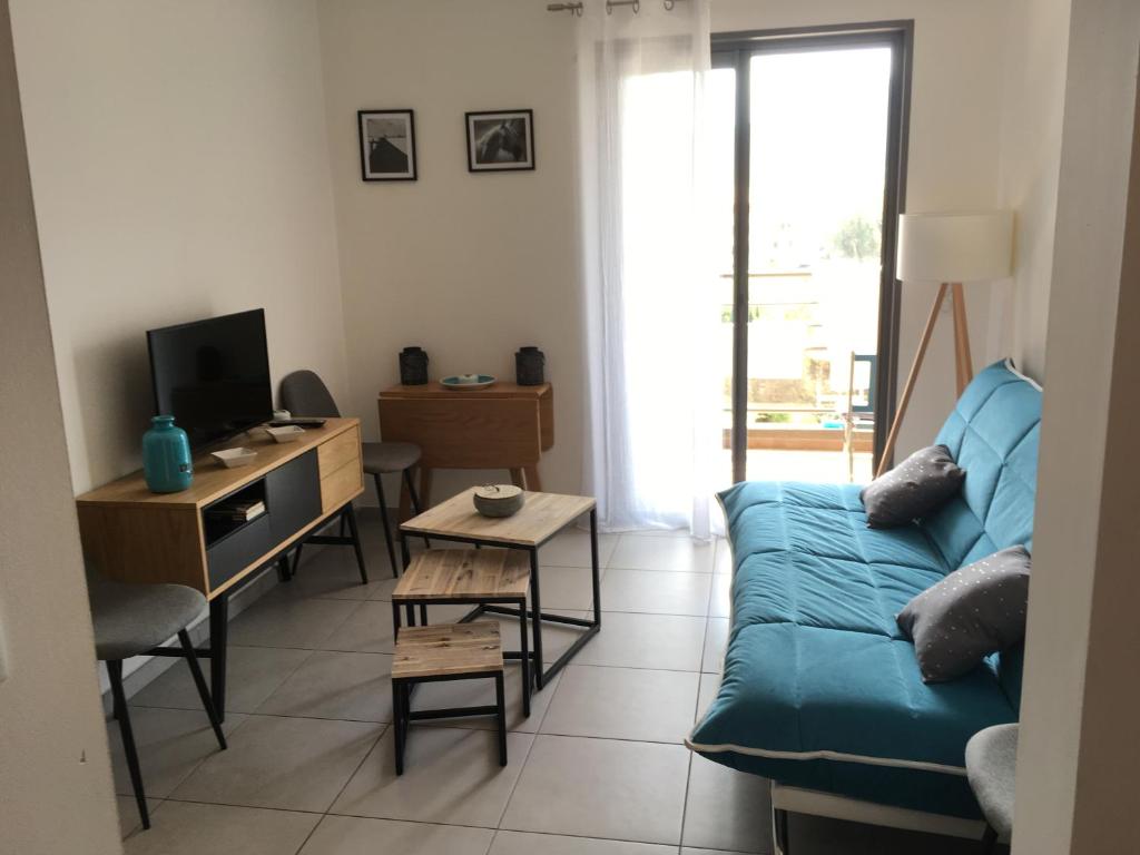 - un salon avec un canapé bleu et un bureau dans l'établissement Appartement Le grand large Proche plage & ville, à Calvi
