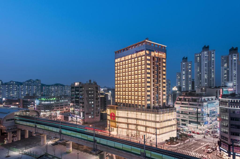 een hoog gebouw in een stad met een trein bij Ramada by Wyndham Incheon in Incheon