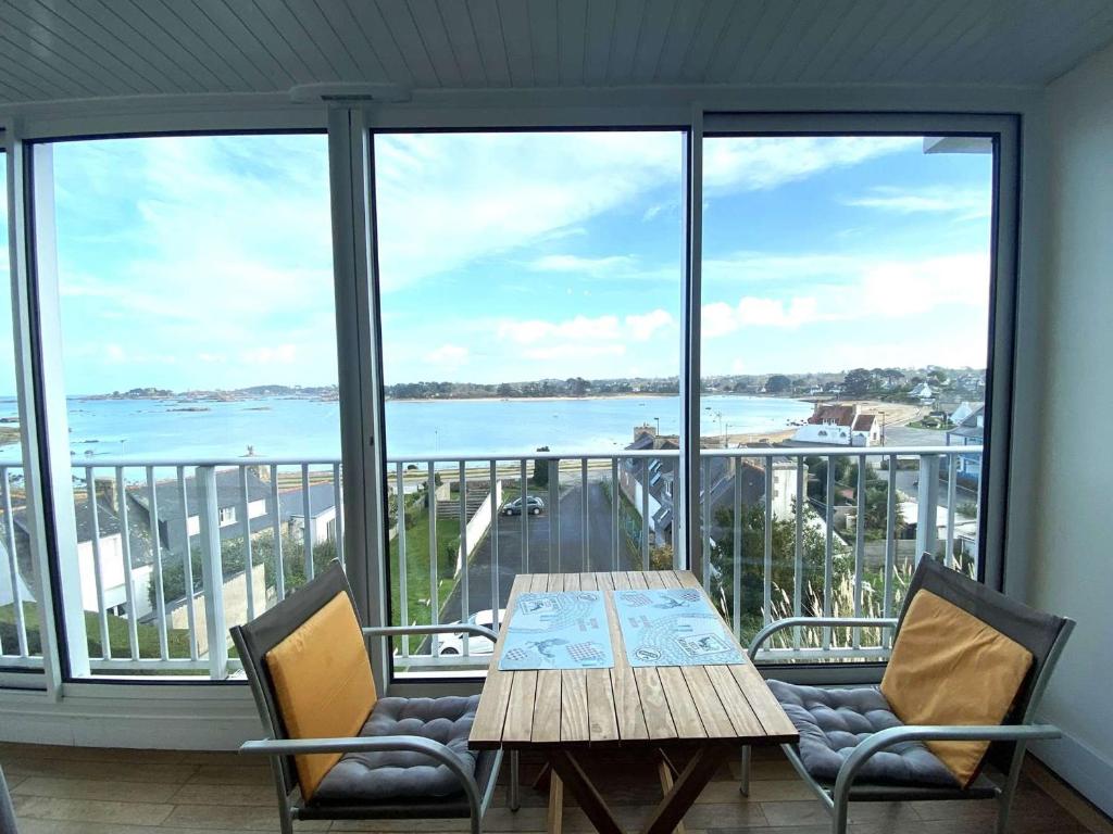 une table et des chaises sur un balcon avec vue sur l'océan dans l'établissement Appartement 3* à Trégastel avec WIFI, parking, animal admis - FR-1-368-441, à Trégastel