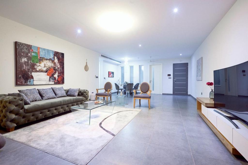 a living room with a couch and a tv at Cozy 2-Bedroom behind West Hills Mall in New Weija