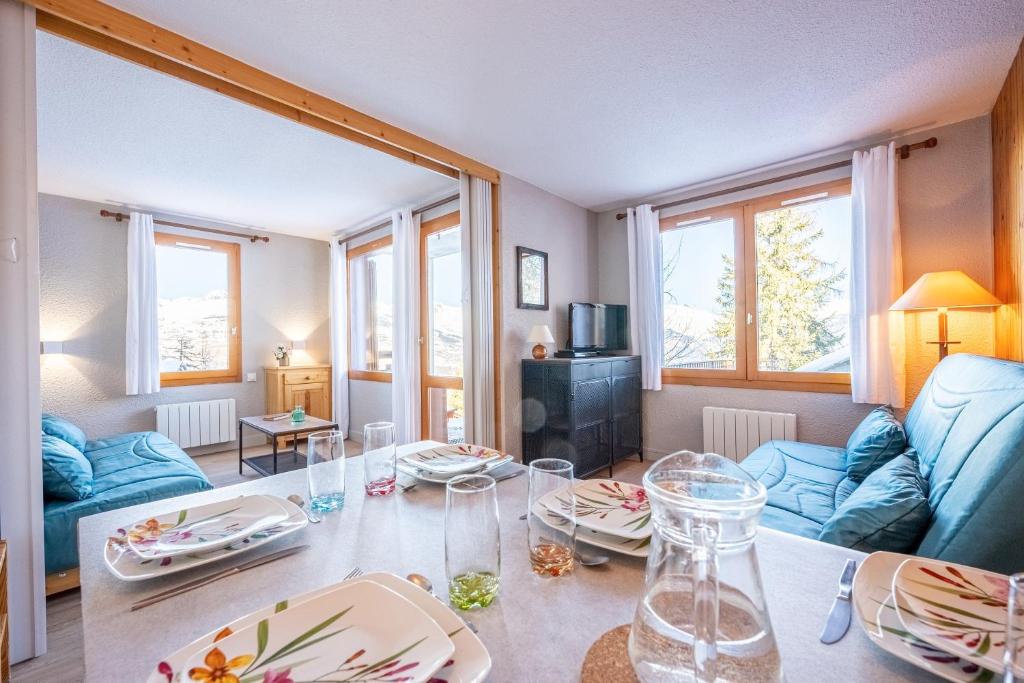 un salon avec une table et un canapé bleu dans l'établissement Le Sauget- au Chalet Bellevue Domaine La Plagne Paradiski, à Mâcot La Plagne