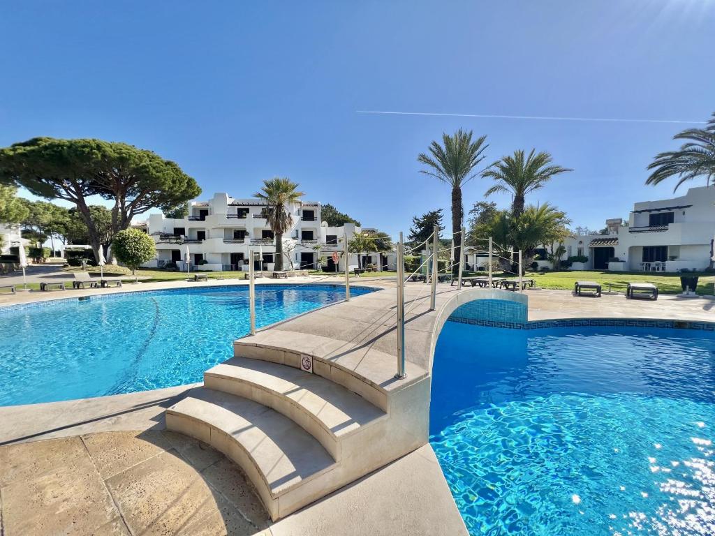 a swimming pool with palm trees and buildings at Albufeira Balaia Golf Vilage 4 With Pool by Homing in Albufeira