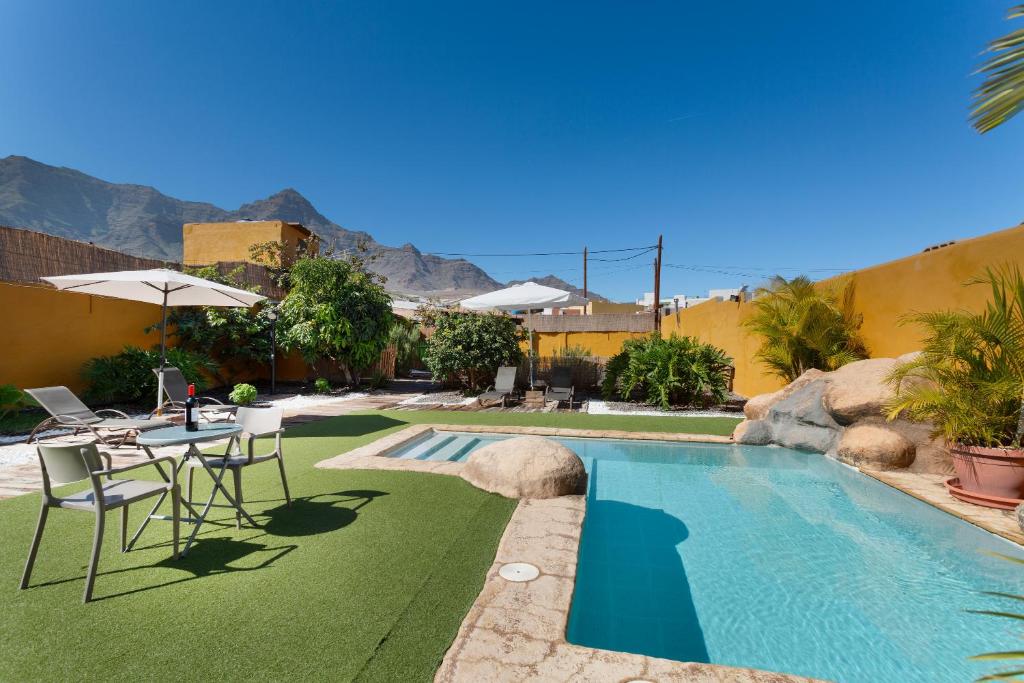 a pool with a table and chairs next to a house at Vivienda Vacacional Folillo in La Aldea de San Nicolas