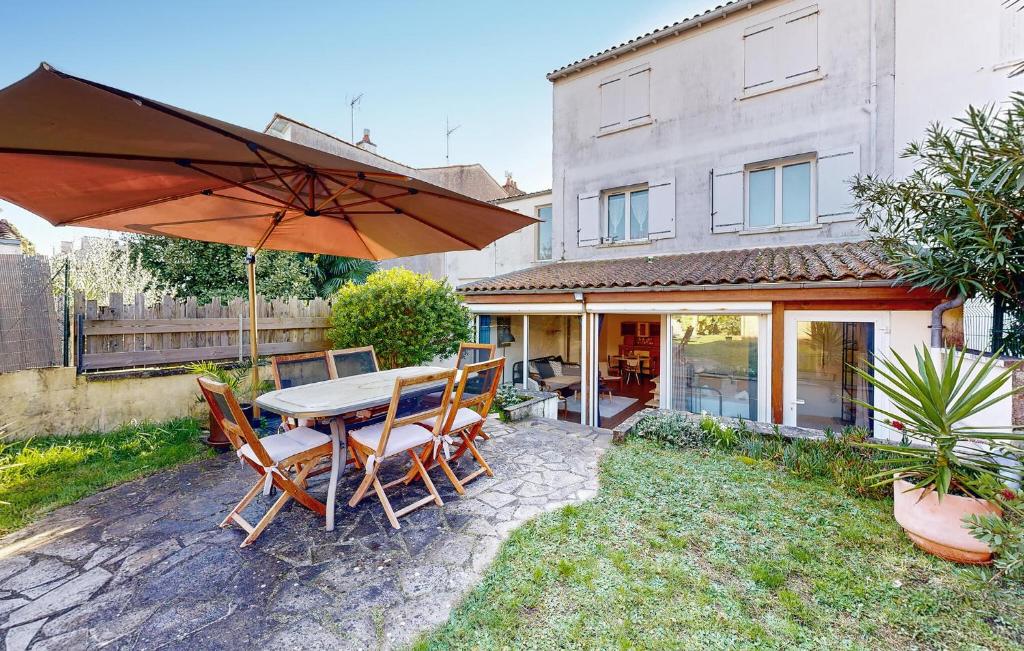 un patio avec une table, des chaises et un parasol dans l'établissement 1 Bedroom Stunning Apartment In Royan, à Royan