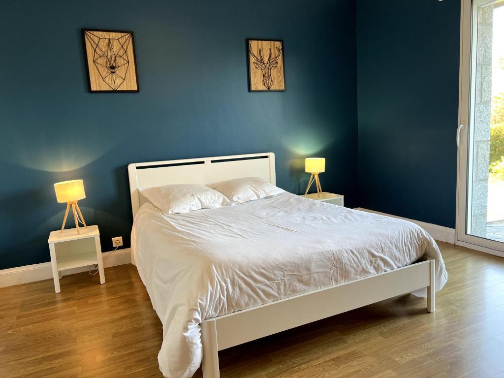 une chambre avec un lit aux murs bleus et deux lampes dans l'établissement Granit Cocon 4p Madame est servie, à Saint-Quay-Perros