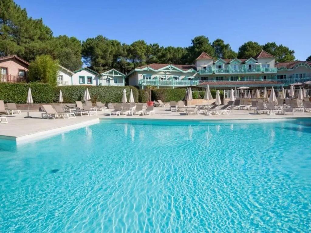 a pool at a resort with chairs and umbrellas at Maison avec jardin à Lacanau – 54 m² in Lacanau