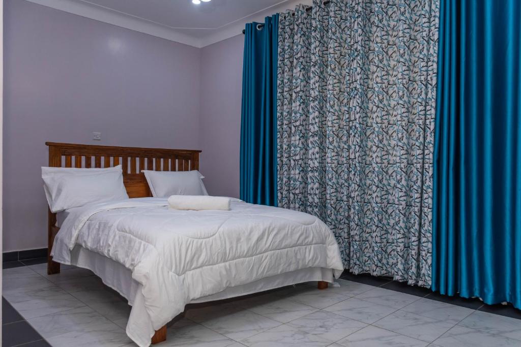 a bedroom with a bed with blue curtains and a bed sidx sidx sidx at Urban Bliss Residence in Bungoma