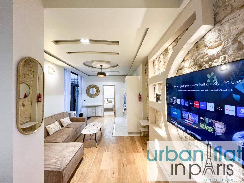 un salon avec un canapé et une télévision sur un mur dans l'établissement Urban Flat - 196 Saint Honore, à Paris