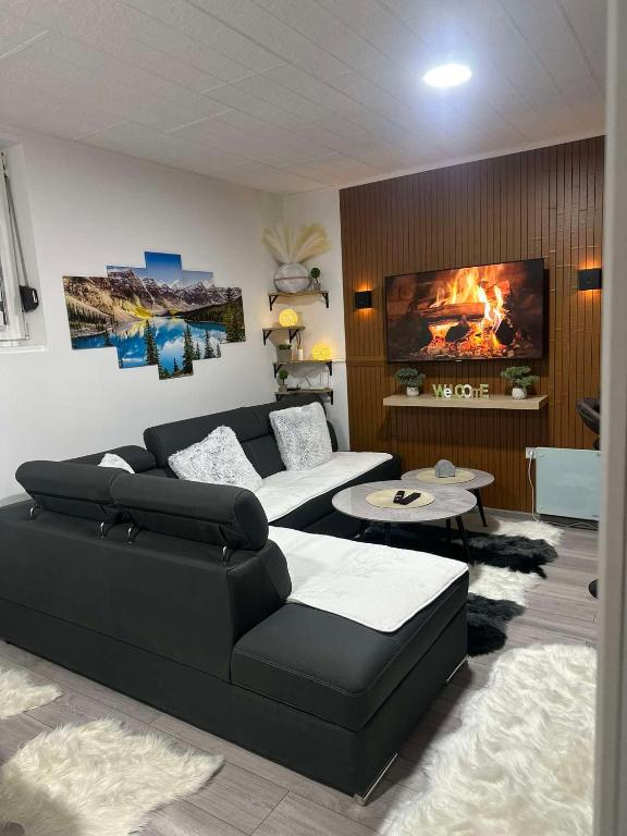 a living room with a black couch and a fireplace at Apartman Bn Vlasic in Vlasic