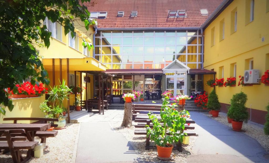 a courtyard of a building with wooden benches and flowers at Botax Motel in Eger