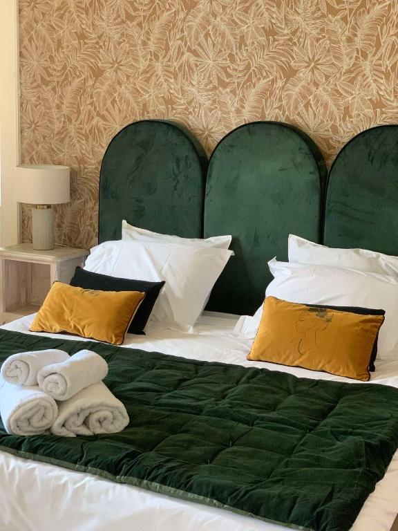 a bed with a green headboard and towels on it at Château Sainte Colombe in Saint-Geniès-des-Mourgues