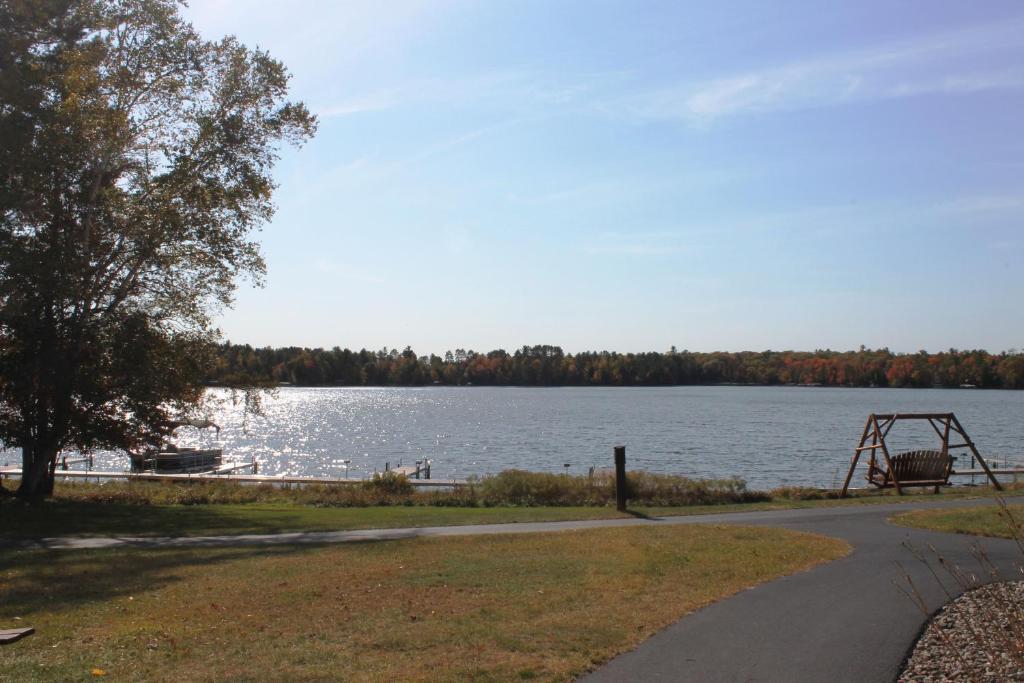 a path next to a lake with a tree and a swing at 2 Bedroom Accessible condo, #114 Wild Eagle Lodge in Eagle River
