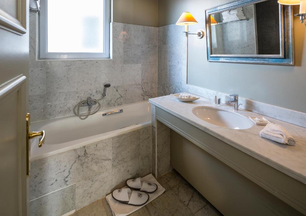 a bathroom with a sink and a tub and a mirror at Le Cavendish in Cannes