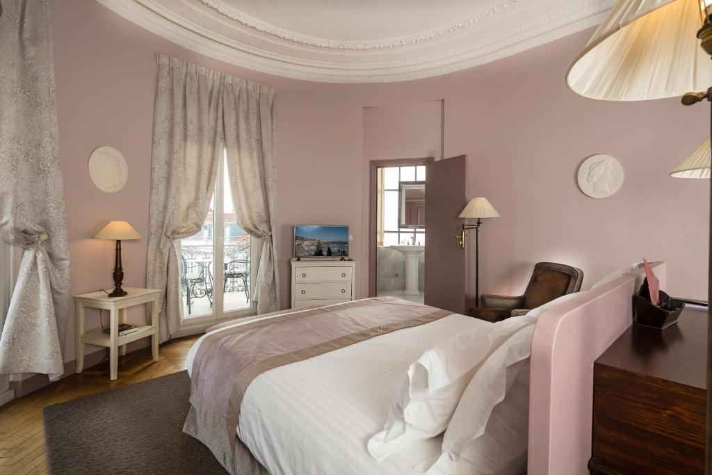 a bedroom with a large white bed and a window at Le Cavendish in Cannes
