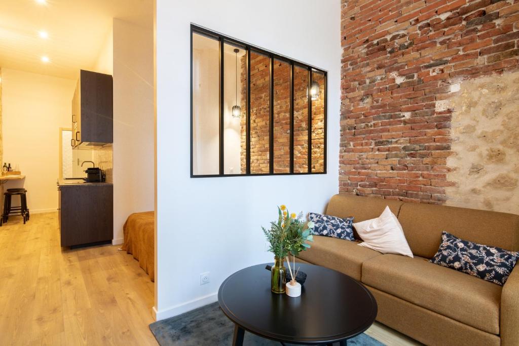 un salon avec un canapé et un mur de briques dans l'établissement Cozy Apartment in heart of Montmartre, à Paris