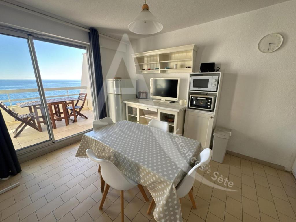 une cuisine avec une table et une vue sur l'océan dans l'établissement 40 M², 1ERE LIGNE MER, DERNIER ETAGE AVEC ASCENSEUR, à Sète