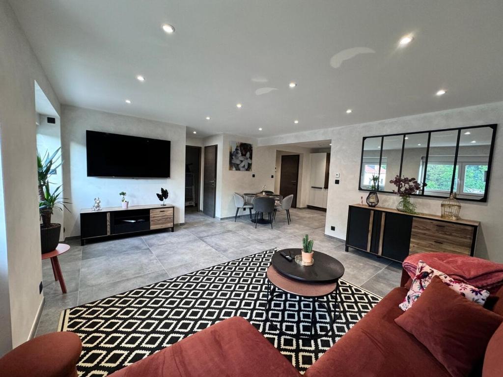 un salon avec un canapé et une télévision dans l'établissement Le Logis des Fées, à Gérardmer