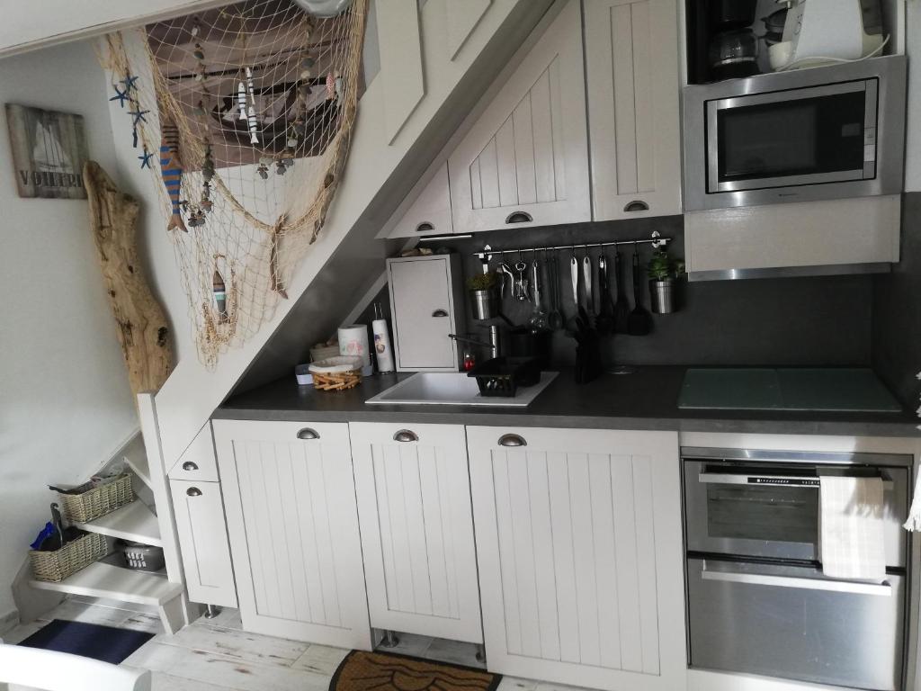 une cuisine avec des armoires blanches et un évier dans l'établissement Brise Marine, à Merville-Franceville-Plage