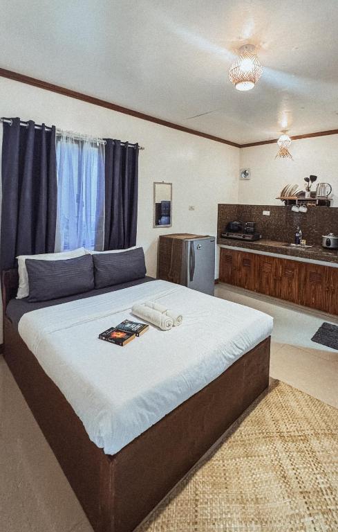 a bedroom with a large bed and a kitchen at Ameeza Houze Homestay - Siargao in General Luna