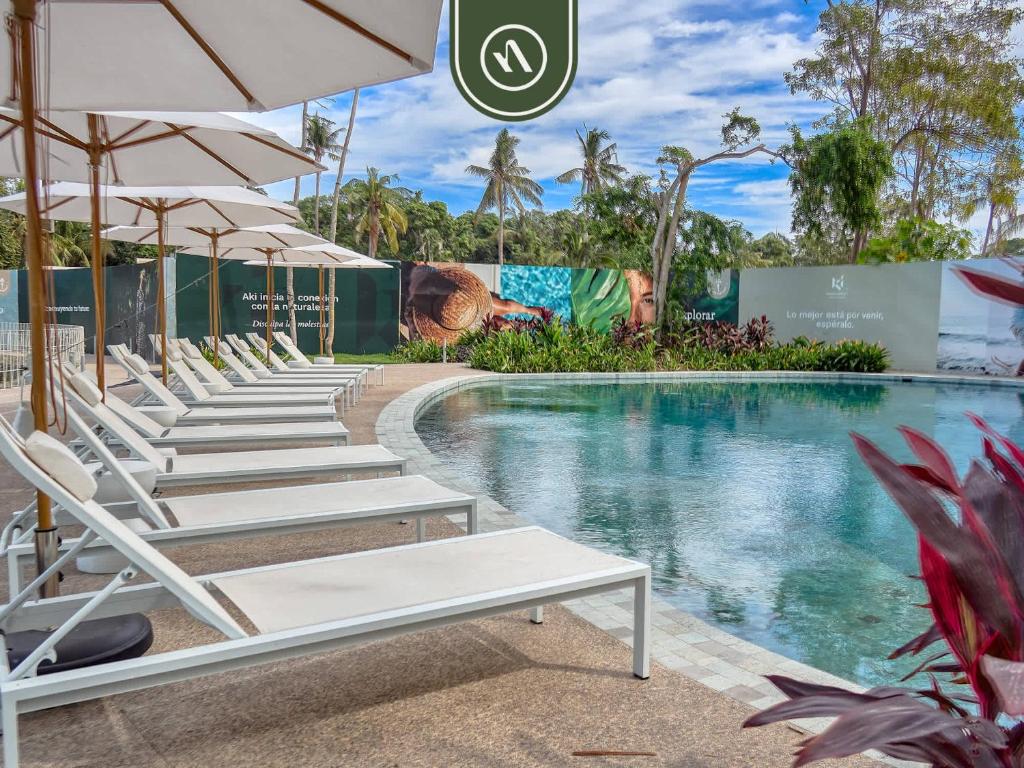 eine Reihe von Liegestühlen und Sonnenschirmen neben einem Pool in der Unterkunft Luxury 2 BR Condo Near Beaches - Pools - Gym in Nuevo Vallarta