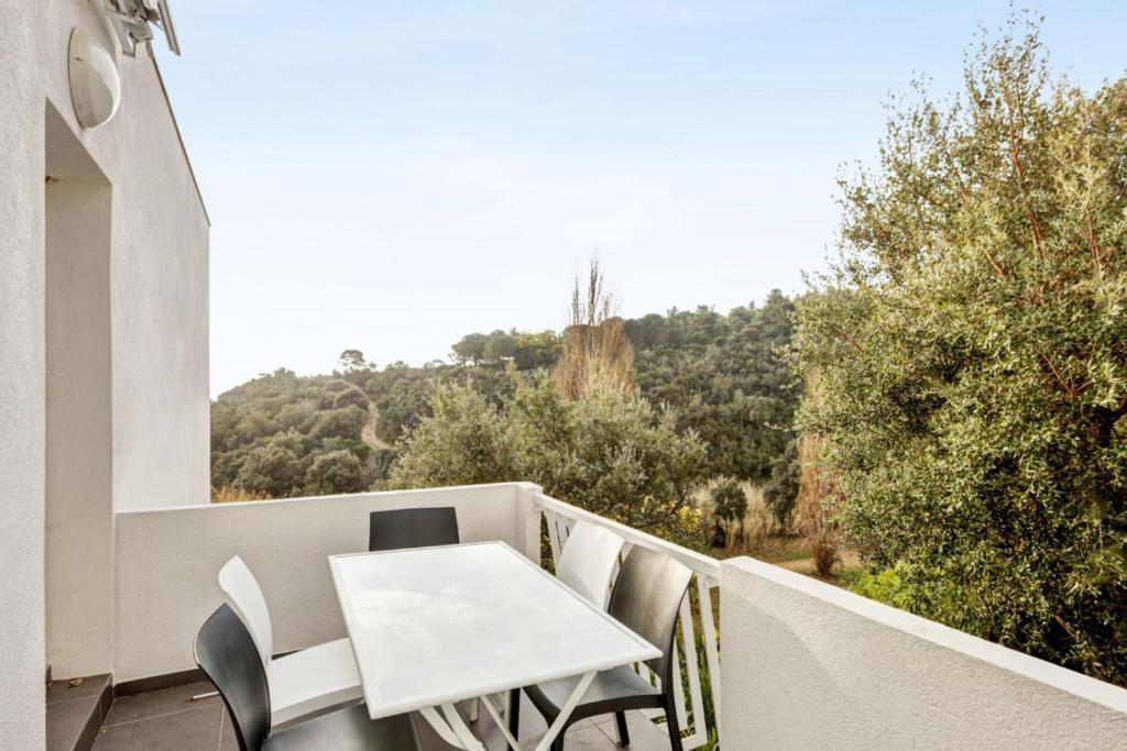 une table blanche et des chaises sur un balcon avec vue dans l'établissement Appartement Dattier - Welkeys, à Cavalaire-sur-Mer
