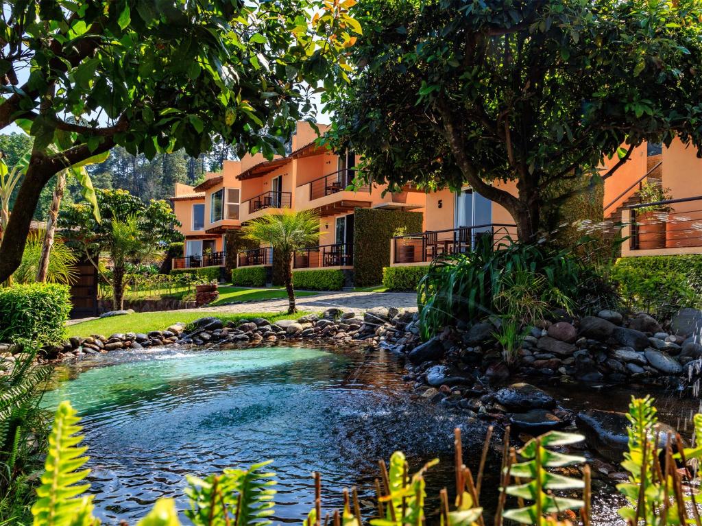 a garden with a pond in front of a building at Hotel Campestre, Valle de Bravo in Valle de Bravo