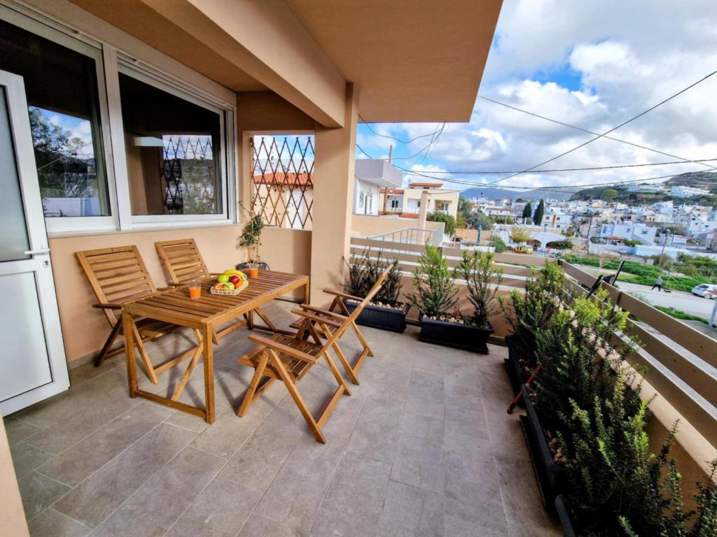 a patio with a wooden table and chairs on a balcony at Mea Casa Comfort Home in Pitsidia