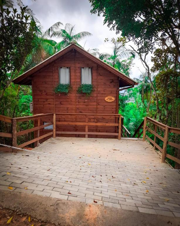 a wooden cabin with two windows and a fence at Chalé Morada dos Tucanos in Santo Amaro da Imperatriz