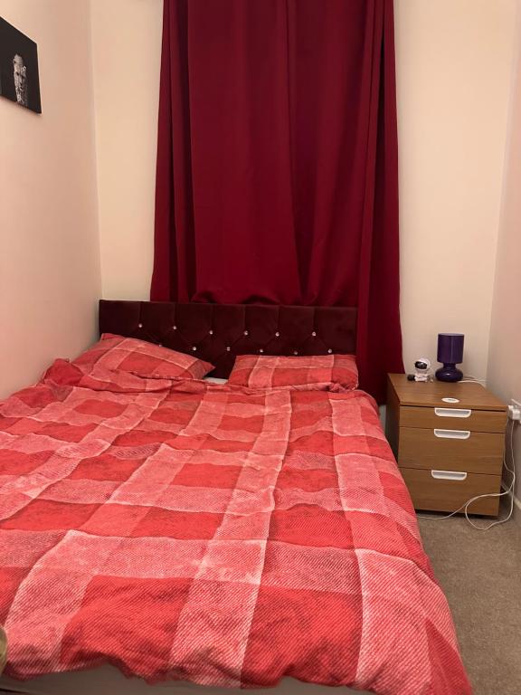 1 dormitorio con cama roja y cortina roja en Hanham Lodge, en Longwell Green