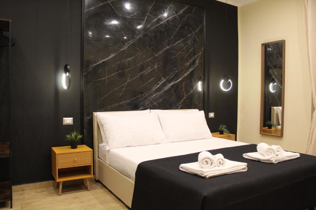 a bedroom with a bed with two towels on it at BlackWoody Contemporary Rooms - Napoli Centro Storico Via Toledo in Naples