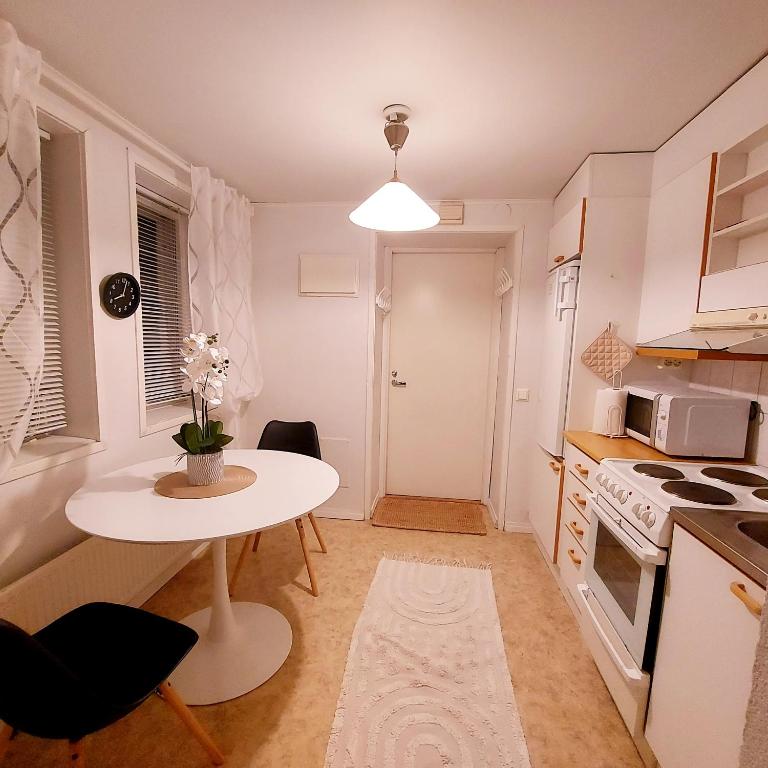 a small kitchen with a white table and a small table with flowers at Huoneisto Pikku Neristan in Kokkola